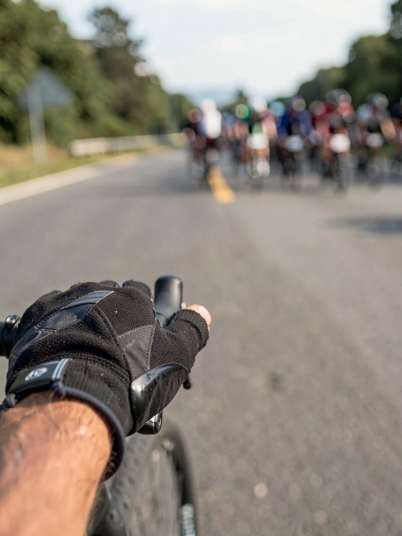 A pack of amateur road cyclists leaning into a fast corner on a closed city circuit, metal barriers at the edge of the road, motion blur on the wheels